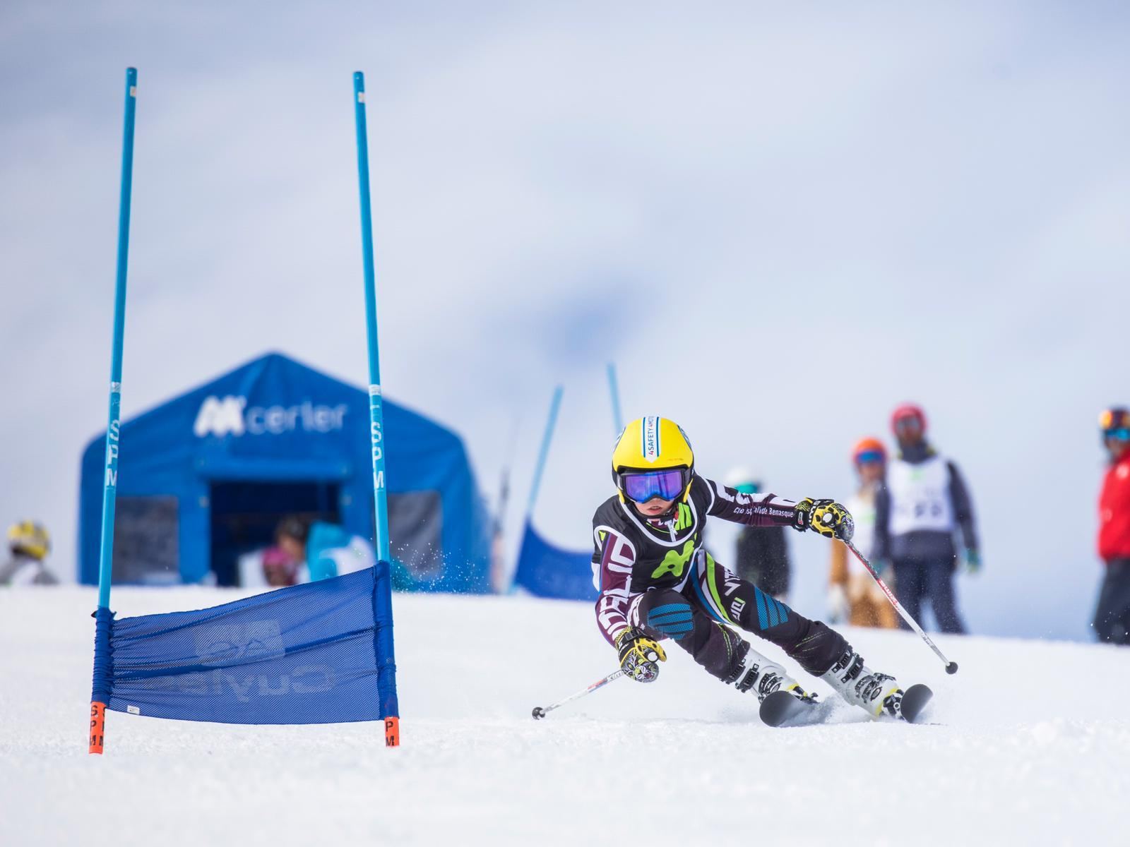 Deportista joven del Club Esquí Valle de Benasque pasa junto a una puerta azul en una carrera en Cerler.