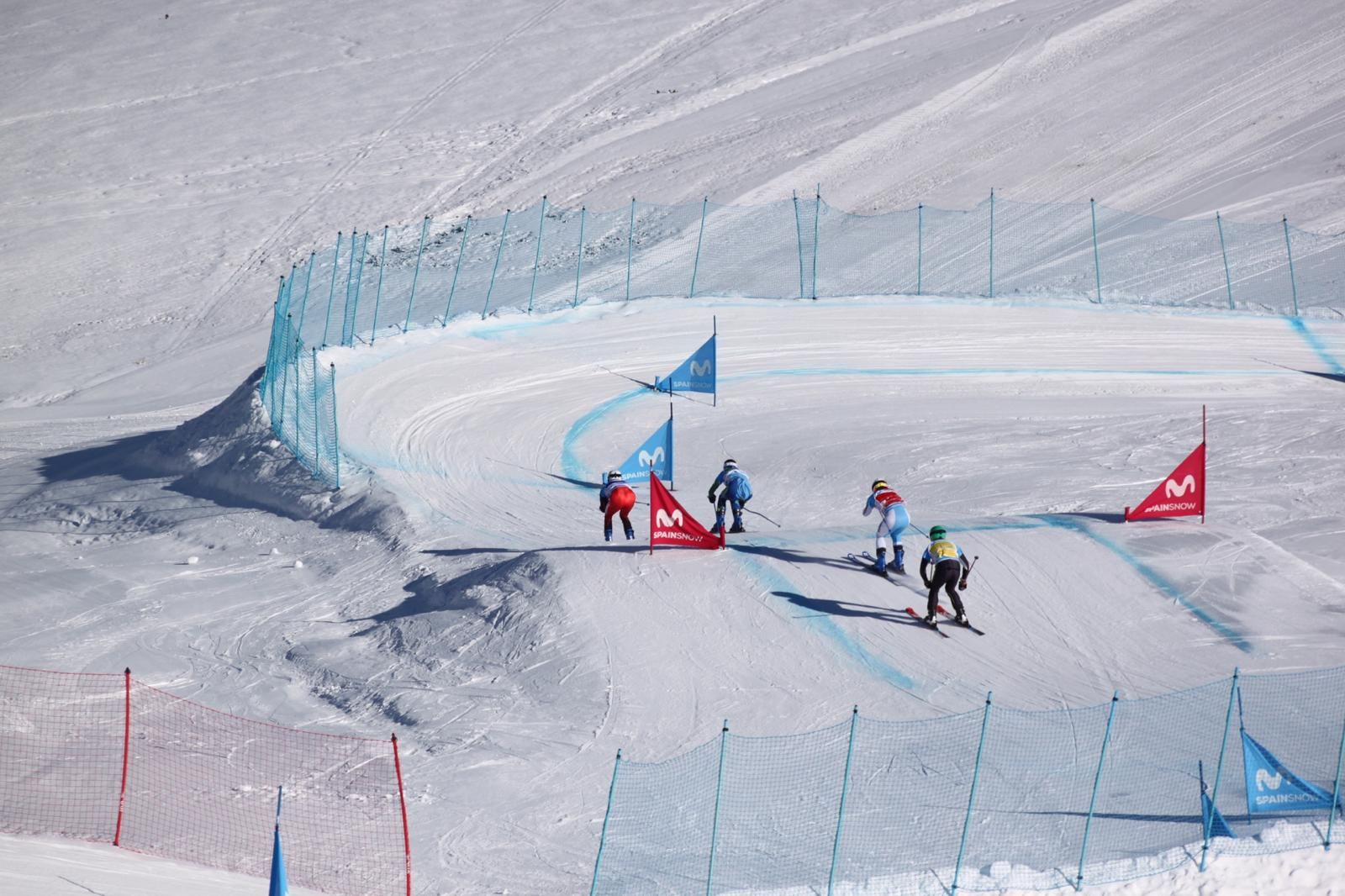Cuatro corredores de skicross trazan un peralte del circuito, entre redes y puertas.
