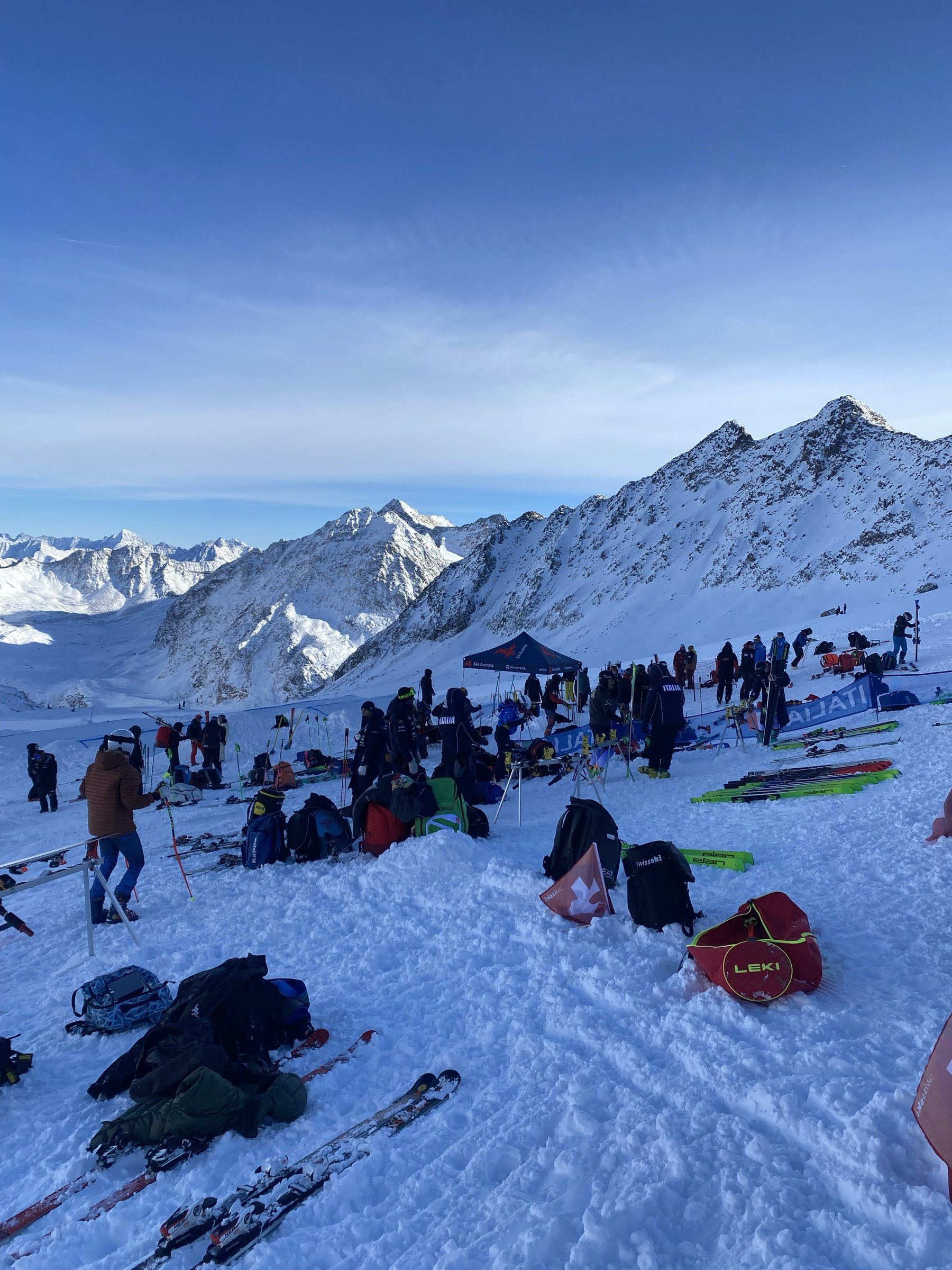 Zona de equipos junto al circuito de Pitztal, con esquís, bolsas y carpas, y las cumbres nevadas detrás.